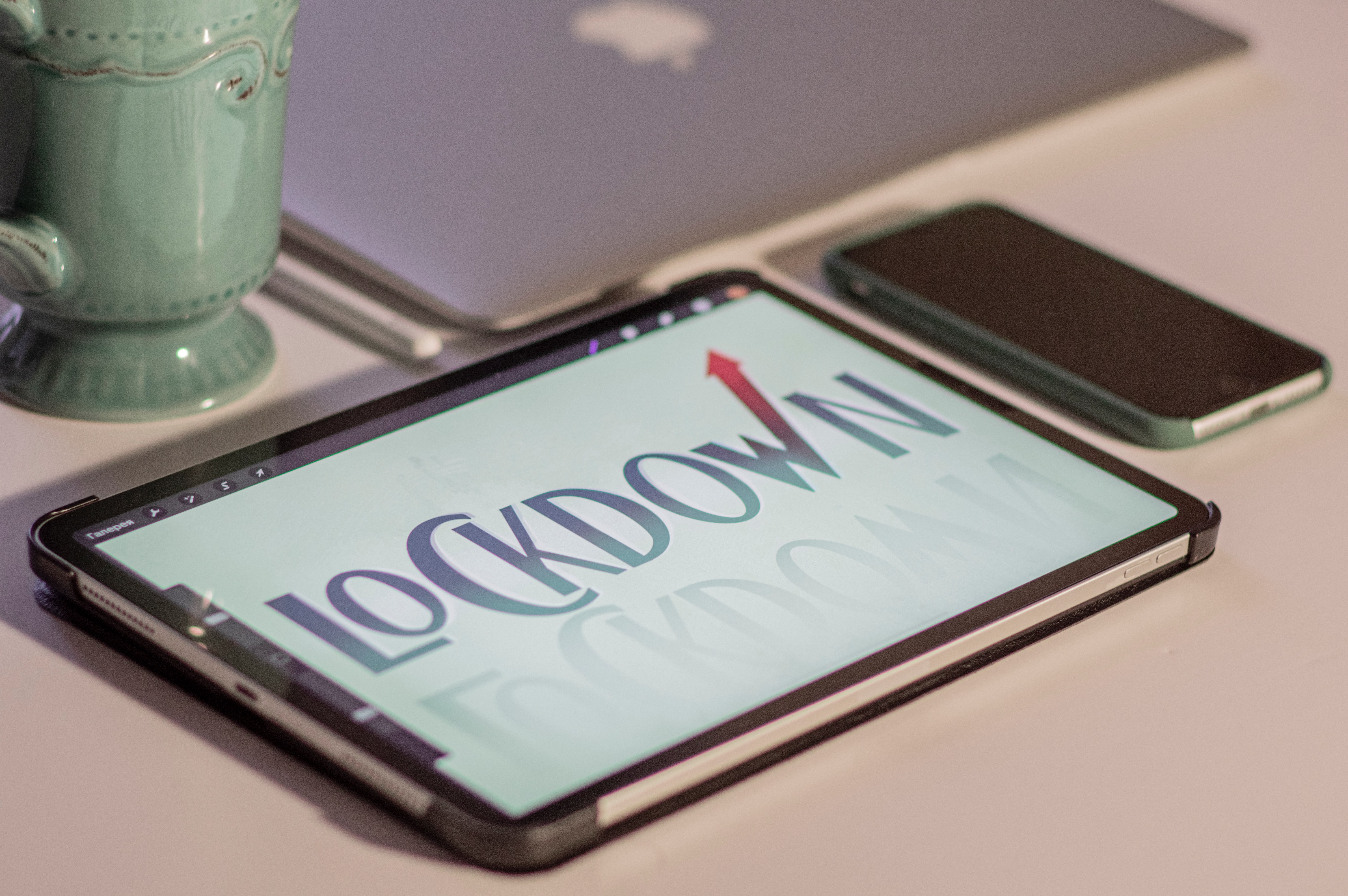 Image of a tablet screen with "Lockdown" displayed, on a table next to a phone and mug.